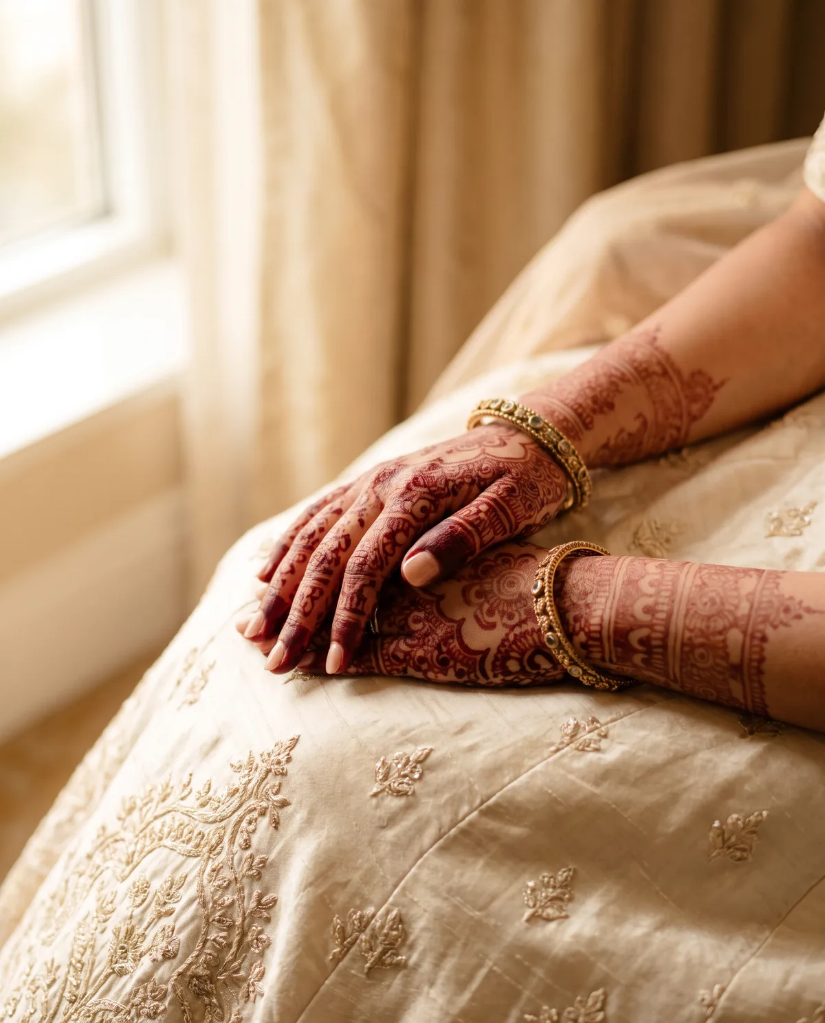 Henna-adorned hands resting on an ivory lehenga