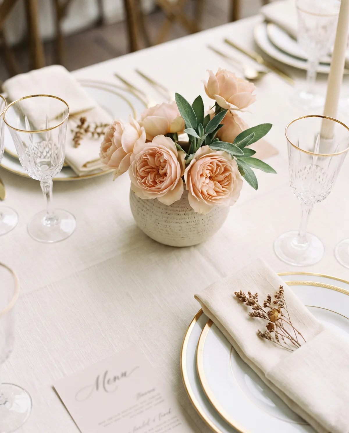 An ivory wedding table setting with blush garden roses
