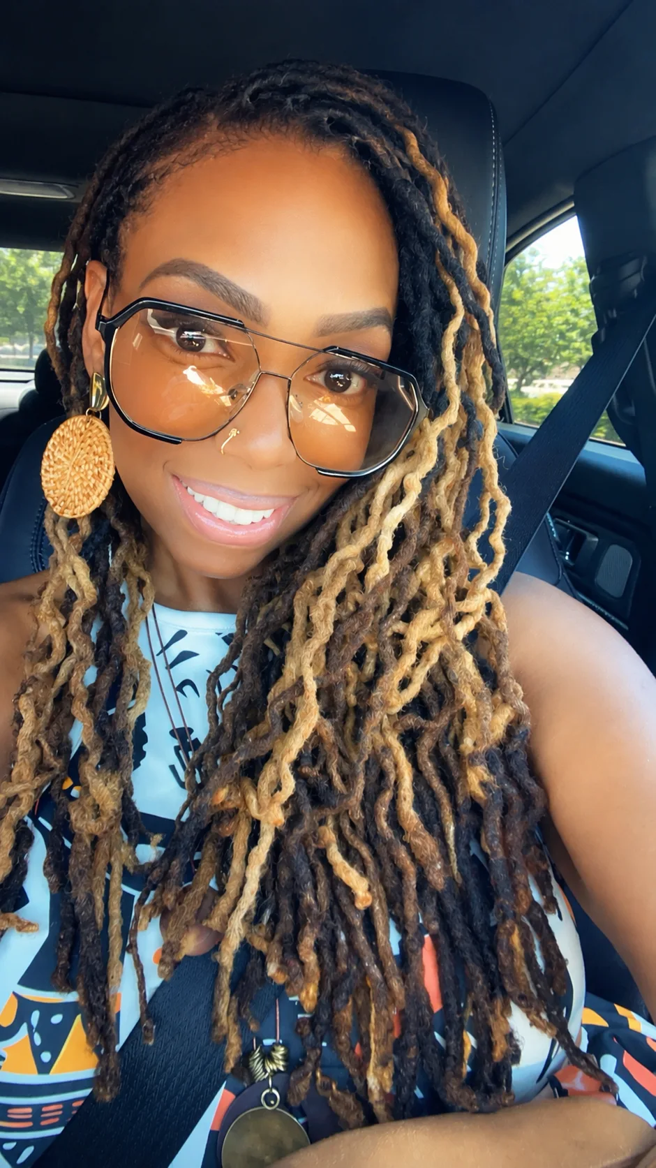Dr. Brooke's real photo — a car selfie in aviator glasses with long locs